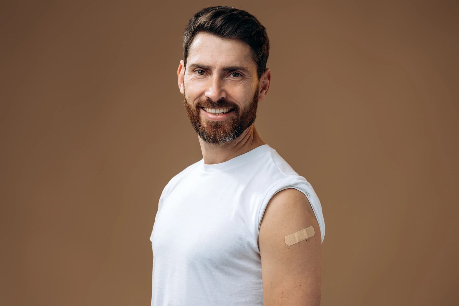 Pharmacist administering a vaccine injection to a patient's upper arm in a clinical setting.